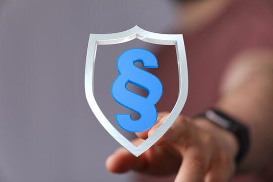A hand touches a shield with a blue section sign, symbolizing legal protection, security, and the concept of law and order. Ideal for illustrati