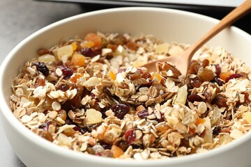 Making granola. Bowl with oat flakes, honey and dried fruits on table, closeup