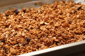 Tasty granola with dried fruits in tray on table, closeup