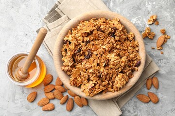 Tasty granola with dried fruits and honey on light grey table, flat lay