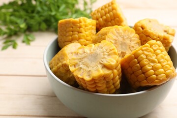 Pieces of tasty corn cobs and parsley on white wooden table, closeup