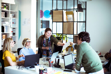 Smiling adult coworkers sharing document in modern office