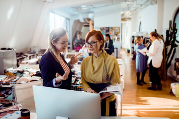 Adult women smiling while discussing project in creative studio