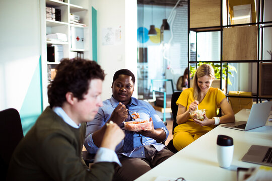 Adult coworkers smiling during lunch break in modern office
