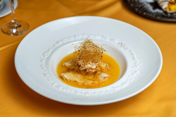 Crepes Suzette dessert plated with orange sauce and caramel threads, offering an elegant gourmet presentation in a refined restaurant environment.
