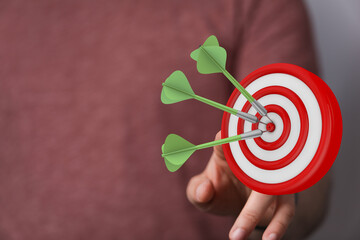 Close up of a hand holding a dartboard with darts on it. Business concept, hitting the target....
