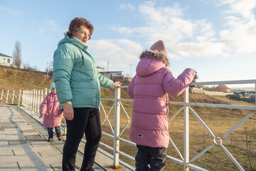 Happy moments with grandmother and little granddaughters walking in the park at autumn morning