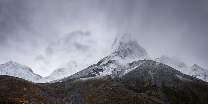 Mt. Ama Dablam summit in the fog, view from Dingboche village on Everest base camp trekking. Himalaya mountains in autumn in stormy weather. - Powered by Adobe