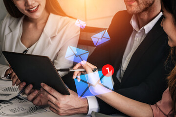 Business professionals collaborate in a modern office while discussing digital communication strategies featuring email icons and a tablet, highlighting teamwork and innovation. Gantry