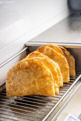 Golden crispy halal tatar chebureks draining on metal rack