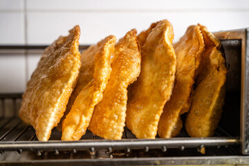 Golden crispy halal tatar chebureks lined up on rack