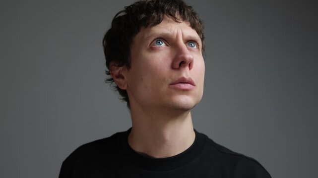 Man hearing distant explosion and air raid sound, anxious portrait looking up in fear