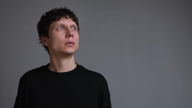 Man hearing distant explosion and air raid sound, anxious portrait looking up in fear