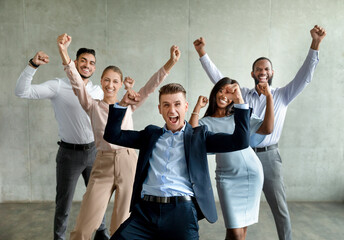 In a modern corporate office, a diverse group of business professionals exclaims with joy, raising their fists in celebration. Their expressions show excitement and pride over a company achievement.
