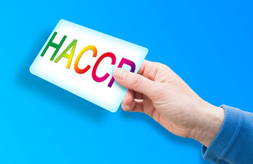HACCP (Hazard Analyses and Critical Control Points) - Food Safety and Quality Control in food industry concept with text and hand holding a card