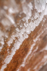 Ice crystals and frozen droplets on a yellow and ochre rock inside a glacier.