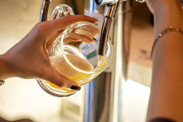 Hand pouring draft drink into clear glass mug