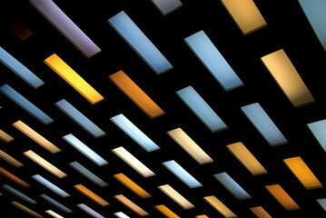 Abstract background, multi colored rectangles on black background. Ceiling hanging yellow, blue, lilac, white lamps on black background