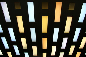 Abstract background, multi colored rectangles on black background. Ceiling hanging yellow, blue, lilac, white lamps on black background