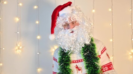 A man dressed as Santa Claus on a white background with festive lights, quietly dancing and enjoying the holiday mood in a playful festive scene.