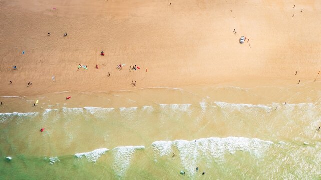 Aerial view of golden sand meeting the turquoise sea, forming a vibrant contrast along the coastline, Newquay, England, United Kingdom.