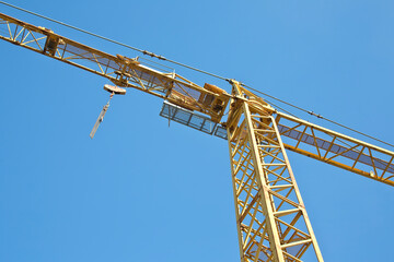 Tower crane in a construction site against a blue sky - construction industry concept