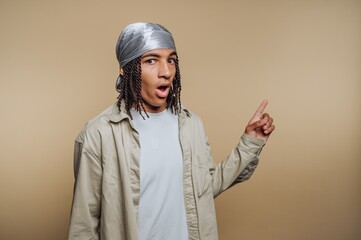 Young man with braided hair and durag pointing to the side.