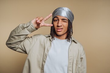 Young person with a durag making a peace sign, winking