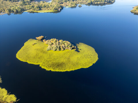 Aerial view of a vibrant green island surrounded by the tranquil, deep blue waters, a serene jewel nestled in the heart of nature, Killarney, County Kerry, Ireland.