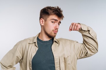 Young man in casual attire flexing his arm, confident pose.