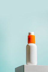White sunscreen spf bottle with orange cap on light blue background. Vertical layout, clean and minimal style, suitable for skincare branding, summer product mockups, or ads