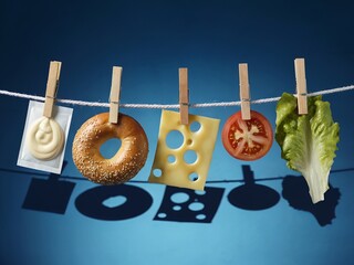 Abstract burger concept. Mayonnaise, bagel, cheese, tomato, and lettuce are pinned with clothespins on a clothesline, blue background and strong shadows.