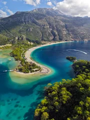 Aerial view of green pine trees, clear turquoise water and mountains in the background in Oludeniz, Turkey. Flying over famous blue lagoon in Oludeniz © SJ Travel Footage