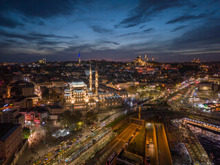New Mosque - Yeni Camii - illuminated in Istanbul, against red morning sky. Aerial shot of skyline of Istanbul at sunrise with beautiful lights and historic architecture along Bosphorus