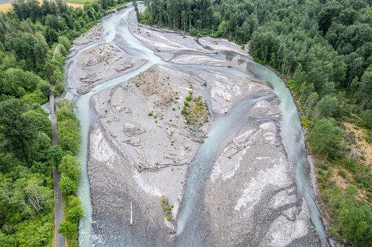 Aerial view of the Carbon River's braided channels weaving through gravel bars and lush green forests, a testament to nature's artistry, Orting, Washington, United States.