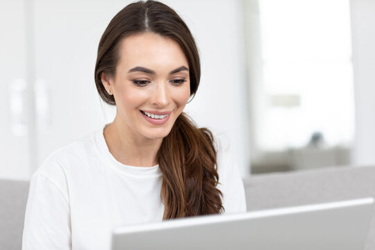 Woman smiling and looking at a laptop.