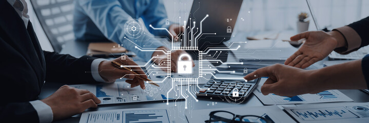 A business team engages in a cybersecurity project, showcasing collaboration with a digital lock symbol and circuit patterns on the workspace for data safety. Trope