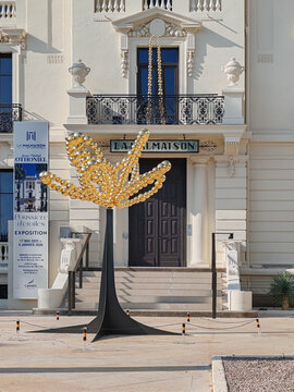 Cannes, France - June 7, 2025: Golden contemporary sculpture in front of La Malmaison art center on Croisette promenade