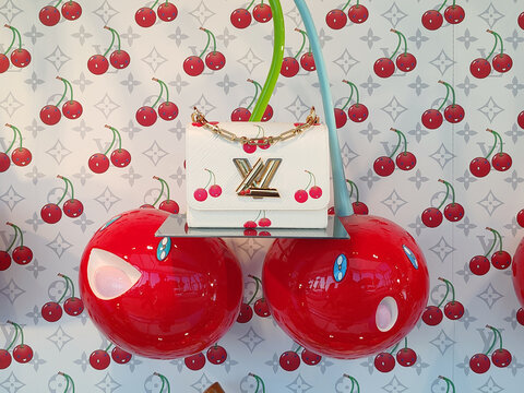 Cannes, France - 7 June 2025: Louis Vuitton boutique window on La Croisette featuring cherry themed handbags displayed against playful cherry pattern backdrop