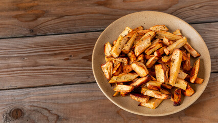 Baked parsnip roots with honey and thyme on a plate. Wooden table with copy space. 