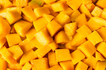 Peeled, ripe mango fruit pieces. Background texture.