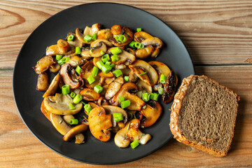 Fried champignon mushrooms with scallions and a slice of bread. European healthy vegan dish. 