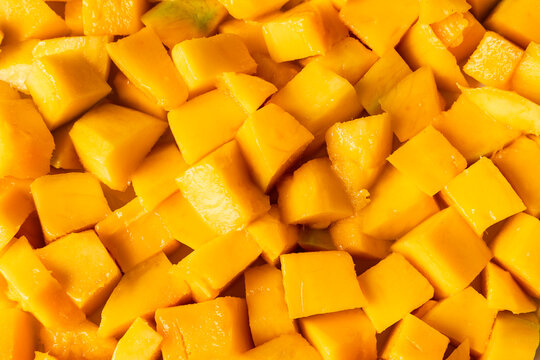 Peeled, ripe mango fruit pieces. Background texture.