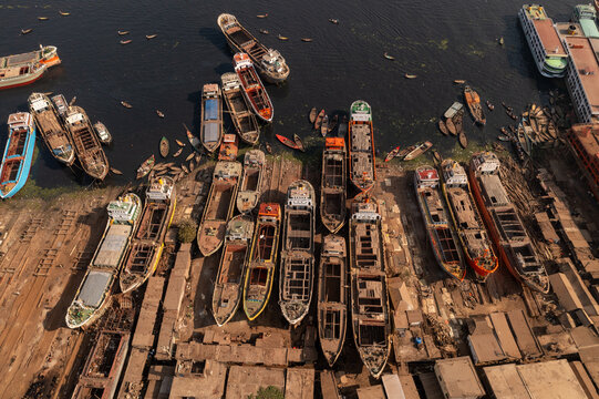 Aerial view of old cargo ships and boats docked along the Buriganga River, their weathered hulls a testament to time and tide, Dhaka, Dhaka Division, Bangladesh.