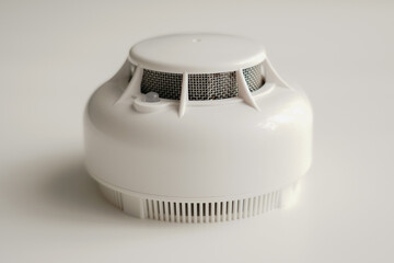 White smoke detector on a light background, showing modern fire safety equipment designed for early...