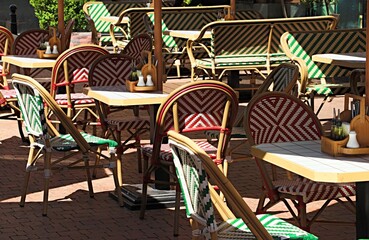 The open veranda of the restaurant, tables and armchairs are illuminated by the warm rays of the evening sun