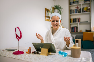 Young woman at home records a beauty vlog on her tablet, sharing skincare and makeup tips with her audience.