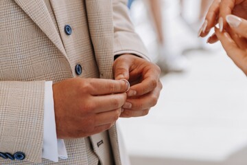 Fototapeta premium Groom carefully taking the wedding ring out of a small wooden ring box, preparing for the exchange during the marriage ceremony