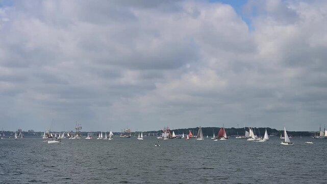 Segelboote und Yachten auf ruhigem Wasser mit bewaldeter K&uuml;stenlinie und bew&ouml;lktem Himmel, Windjammer Parade Kiel 2025, Heikendorf, Kreis Pl&ouml;n, Kieler F&ouml;rde, Schleswig-Holstein, Deutschland, Europa 