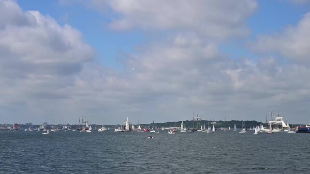 Segelboote und Yachten auf ruhigem Wasser mit bewaldeter K&uuml;stenlinie und bew&ouml;lktem Himmel, Windjammer Parade Kiel 2025, Heikendorf, Kreis Pl&ouml;n, Kieler F&ouml;rde, Schleswig-Holstein, Deutschland, Europa 